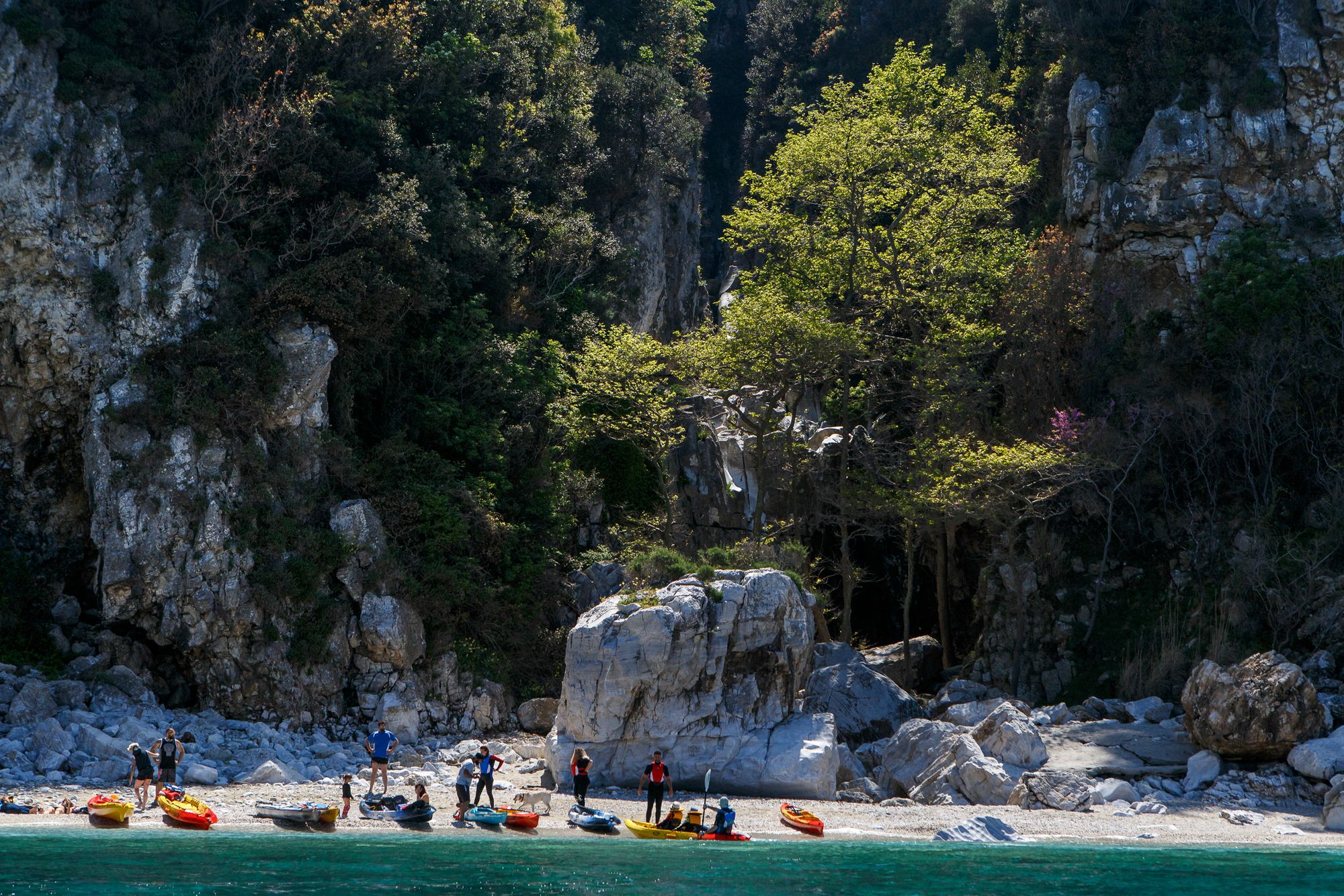 Un groupe de kayakistes sur une plage avec un fond rocheux dans la péninsule du Pélion, en Grèce.